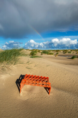 Aangespoeld oranje plastic krat aan de voet van de duinen op de strandvlakte van De Hors van waddeneiland Texel